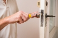 Man fixing the door handle with screwdriver in a new house