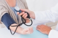 Cropped image of male doctor checking female patients blood pressure in clinic
