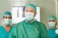 Surgeon with two interns behind him in a surgical room