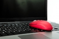 The red computer mouse on the black keyboard