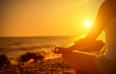 hand of  woman meditating in a yoga pose on beach at sunset