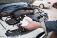 Close up of man checking car engine oil in a car park